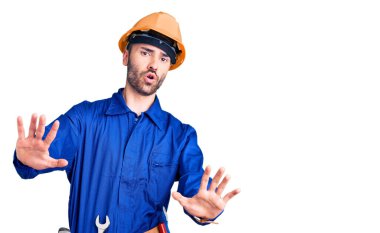 İşçi üniforması giyen genç İspanyol adam avuç içi hareketlerini durduruyor. Öfkeli ve hayal kırıklığı dolu bir ifade. 