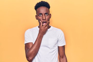 Gündelik giysiler giyen genç Afro-Amerikan erkeği elleri çenesinde olan inançsızlıktan, şaşkınlıktan ve şaşkınlıktan büyülenmiş görünüyor. 
