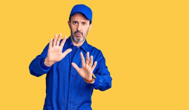 Tamirci üniforması giyen, orta yaşlı yakışıklı bir adam. Avuçlarını hareket ettiriyor. Korkmuş ve iğrenç bir ifadeyle reddediyor. Dur ve yasakla. 