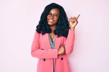 İş ceketi giyen ve yüzünde kocaman bir gülümseme olan güzel Afrikalı kadın kameraya el ve parmak ile bakıyor.. 