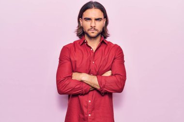 İş kıyafetleri giyen, kuşkucu ve gergin genç bir adam. Yüzünde çapraz kollarla onaylamayan bir ifade var. negatif kişi. 