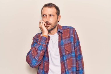 Günlük kıyafetler giyen genç yakışıklı adam gergin ve gergin görünüyor. Ağzı tırnak yiyen eller. anksiyete. 