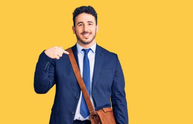 Genç İspanyol takım elbiseli ve deri çantalı adam gülümseyen mutlu ve gururlu birini işaret ediyor. 