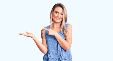 Kolsuz tişört giyen genç, güzel sarışın kadın kameraya hayret ediyor ve gülümsüyor.. 