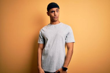 Yakışıklı Afro-Amerikan sporcu sarı arka plan kuşkucu ve gergin, sorun yüzünden surat asıyor. Negatif kişi.