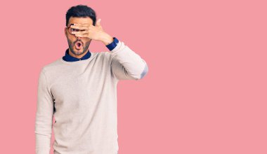 Zarif kıyafetler ve gözlük takan yakışıklı İspanyol adam şok içinde yüzünü ve gözlerini kapayarak utangaç bir ifadeyle parmaklarından bakıyor.. 