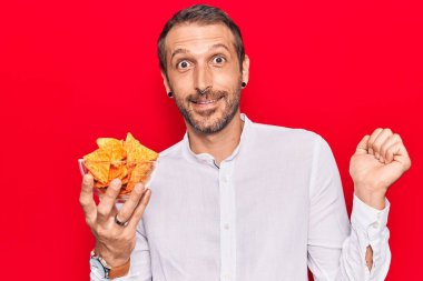 Patates cipsi tutan yakışıklı genç adam gururla bağırıyor zaferi ve başarıyı kutluyor. 