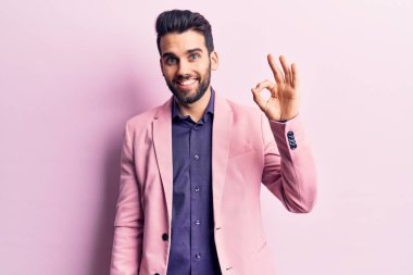 Sakallı, zarif ceketli, gülümseyen, tamam yazan, el ve parmaklı genç, yakışıklı bir adam. başarılı ifade. 