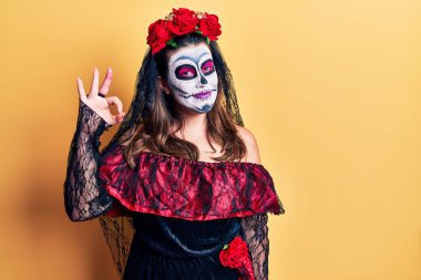 Sarı üzerine ölü kostümü giyip gülümseyen genç bir kadın el ve parmaklarıyla 