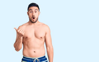 Mayo giyen genç ve yakışıklı bir adam elleri yana işaret ederek şaşırdı, ağzı açık hayret içinde kaldı.. 