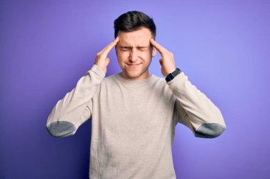 Mor yalıtılmış arka plan üzerine günlük süveter giyen yakışıklı beyaz bir adam. Stres yüzünden başının üstünde baş ağrısı var. Migren ağrısı..