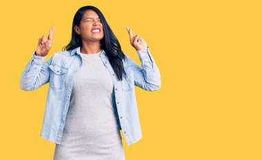 Uzun saçlı, sıradan kot ceket giyen İspanyol kadın umut dolu ve gözleri kapalı bir şekilde gülümseyerek işaret ediyor. Şans ve batıl inançlar. 