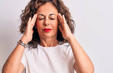 Orta yaşlı, güzel, esmer bir kadın, günlük tişört giyiyor, beyaz arka planda el üstünde duruyor, başı ağrıyor, stres yüzünden. Migren ağrısı..