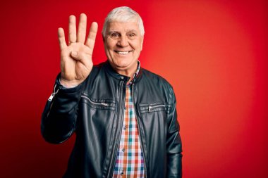 Kıdemli yakışıklı, beyaz gömlekli ve ceketli adam izole edilmiş kırmızı arka planda dört numarayı işaret ederken kendinden emin ve mutlu bir şekilde gülümsüyor..