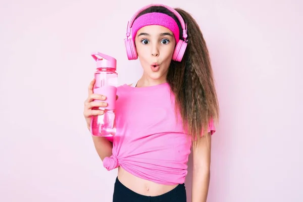 Linda Niña Hispana Usando Ropa Gimnasio Usando Auriculares Sosteniendo Botella —  Fotos de Stock