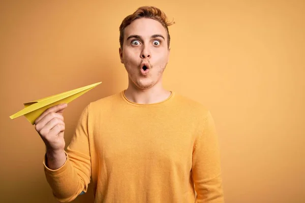 Joven Pelirrojo Guapo Sosteniendo Avión Papel Sobre Fondo Amarillo Aislado —  Fotos de Stock