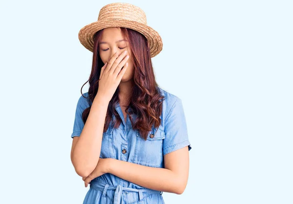 年轻美丽的中国姑娘戴着夏帽 厌烦了打呵欠累了 用手捂住嘴 烦躁不安和困倦 — 图库照片