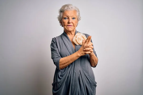 Senior beautiful grey-haired woman wearing casual dress standing over white background Holding symbolic gun with hand gesture, playing killing shooting weapons, angry face
