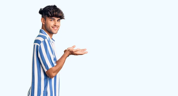 若いヒスパニック系の男は コピースペースを示す手を開いて手のひらで脇を指してカジュアルな服を着て 広告笑顔興奮幸せを提示 — ストック写真