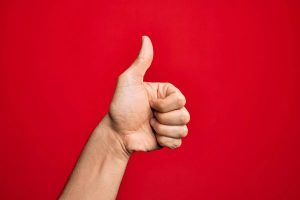 在孤立的红色背景上伸出手指的高加索年轻人的手 手举着大拇指 做着成功的认可手势 验证和积极的符号 — 图库照片