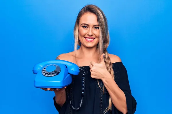 Joven Hermosa Mujer Rubia Sosteniendo Teléfono Vintage Sobre Fondo Azul — Foto de Stock