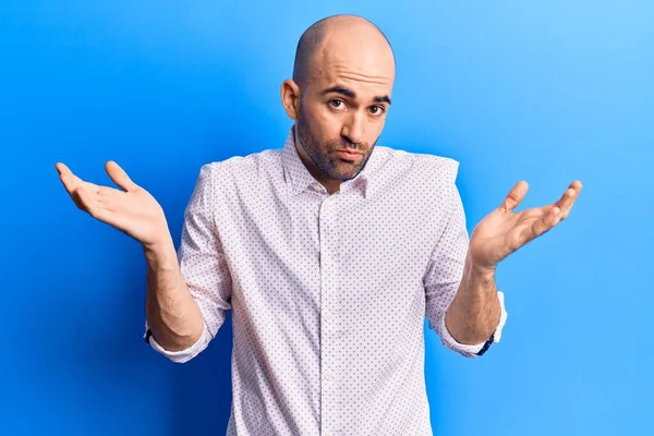 Zarif tişört giyen yakışıklı kel adam habersiz ve kolları açık, hiçbir fikrim yok ve şüpheli bir yüzüm var.. 