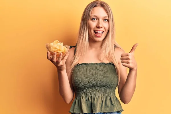 Patates Cipsi Tutan Genç Sarışın Kadın Mutlu Pozitif Gülümsüyor Başparmağıyla — Stok fotoğraf