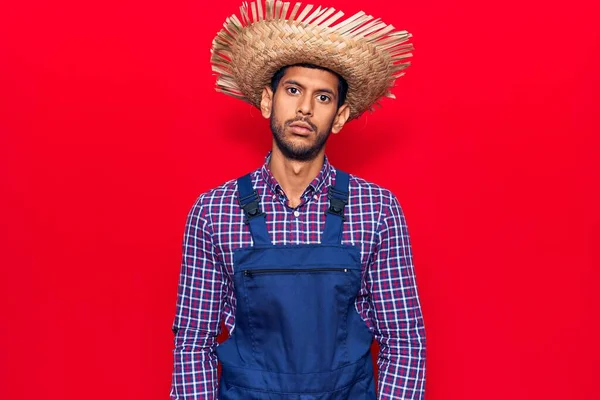 Νεαρός Λατίνος Άντρας Καπέλο Αγρότη Και Ποδιά Χαλαρός Σοβαρή Έκφραση — Φωτογραφία Αρχείου