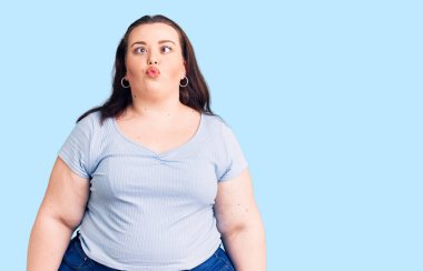 Genç ve cüsseli bir kadın günlük kıyafetler giyiyor, dudaklarıyla balık suratı yapıyor, çılgınca ve komik hareketler yapıyor. Komik ifade. 