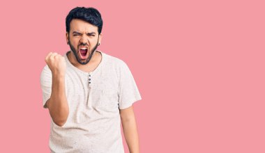 Latin asıllı genç bir adam, kızgın ve kızgın. Öfkeyle bağırırken yumruğunu sallıyor ve öfkeleniyor. öfke ve agresif konsept. 