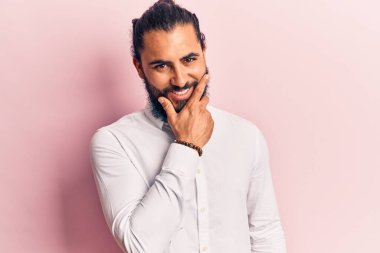 Gündelik giysiler giyen genç bir Arap kameraya kendinden emin bir şekilde bakıyor kollarını kavuşturmuş ve çenesini kaldırmış gülümsüyor. Olumlu düşünmek. 