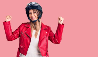 Motosiklet kaskı takan genç ve güzel bir kadın gururla bağırıyor, zaferi kutluyor ve kollarını kaldırarak başarıyı kutluyor. 