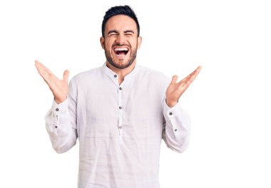 Gündelik kıyafetler giyen genç, çılgın ve çılgın başarıyı kutlayan kollarını kaldırmış, gözlerini kapatmış heyecanlı çığlıklar atan yakışıklı bir adam. Kazanan konsept 