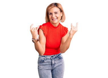 Sıradan kıyafetler giyen, çılgın bir ifadeyle bağıran genç sarışın kadın elleri havada rock sembolü yapıyor. Müzik yıldızı. ağır kavram. 