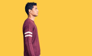 Hispanik yakışıklı genç adam günlük giysiler giyiyor. Tarafını arıyor, rahat poz veriyor. Kendine güvenen bir gülümsemesi var.. 