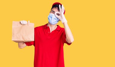 Teslimat üniforması ve tıbbi maske takan genç İspanyol adam gülümsüyor. 