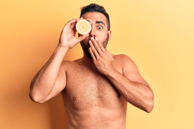 Elle limon kaplayan tişörtsüz, ağzı kapalı duran İspanyol genç adam, şaşırdı ve hata yapmaktan korktu. şaşırmış ifade 