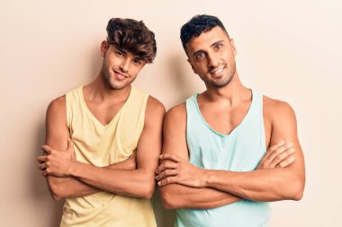 Sıradan kıyafetler giyen, kollarını kavuşturup kameraya bakan mutlu yüzlü genç eşcinsel çift. pozitif kişi. 
