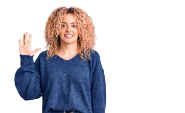 Kıvırcık saçlı, sıradan bir süveter giyen genç, sarışın bir kadın beş numaralı parmaklarıyla işaret ederken kendinden emin ve mutlu bir şekilde gülümsüyor.. 