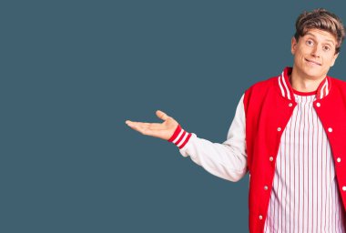 Beyzbol forması giyen, elleri ve kolları havada, kafası karışmış genç ve yakışıklı bir adam. şüphe kavramı. 