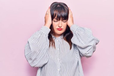 Genç ve cüsseli kadın gündelik kıyafetler giyiyor. Baş ağrısı, çaresiz ve stresli. Çünkü acı ve migren ağrısı var. Eller başının üstünde.. 