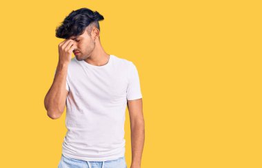 Günlük kıyafetler giyen genç İspanyol adam yorgun burnu ve gözleri ovuşturup yorgun ve baş ağrısı çekiyor. Stres ve hüsran kavramı. 