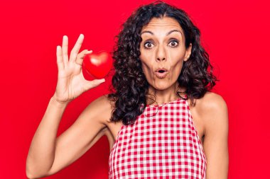 Orta yaşlı, kalbi olan güzel bir kadın. Korkmuş ve ağzı açık bir şekilde şaşırmış. Şaşırmış, inançsız bir yüz. 