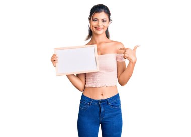 Elinde boş beyaz karatahta tutan genç ve güzel bir kadın mutlu ve gururlu bir kendini işaret ediyor. 