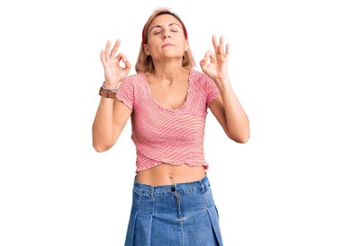 Gündelik kıyafetler giyen genç sarışın kadın ve diadem rahatla ve gözleri kapalı gülümse parmaklarıyla meditasyon hareketi yapıyor. yoga konsepti. 