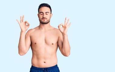 Mayo giyen genç yakışıklı adam rahatla ve gözleri kapalı gülümse parmaklarıyla meditasyon hareketi yapıyor. yoga konsepti. 