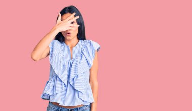 Genç, güzel, latin elbiseli bir kız. Şoka girmiş, yüzünü ve gözlerini kapamış, utanmış bir ifadeyle parmaklarından bakıyor.. 