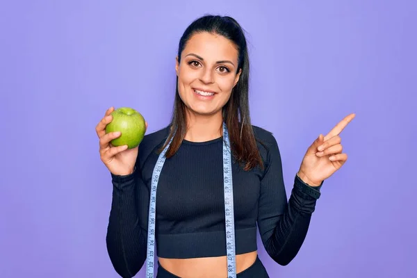 Schöne Brünette Sportliche Frau Mit Maßband Essen Apfelfrüchte Über Lila — Stockfoto