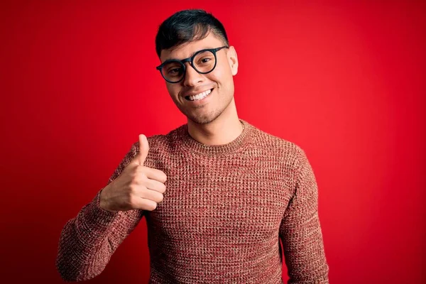 Mladý Pohledný Hispánec Šprtských Brýlích Červeném Pozadí Dělá Šťastné Gesto — Stock fotografie