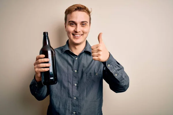 Ung Flot Rødhåret Mand Drikker Flaske Isoleret Hvid Baggrund Smilende - Stock-foto